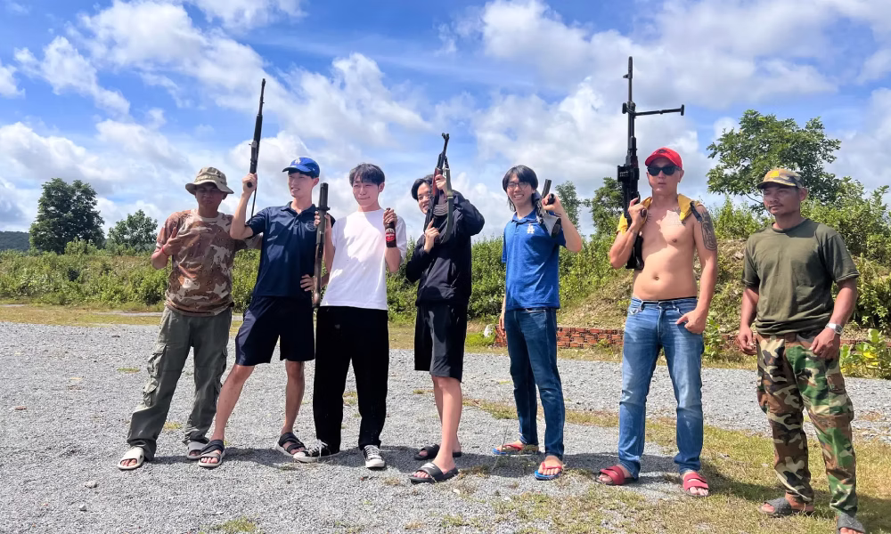 Friends posing with their firearms at the outdoor shooting range near Phnom Penh, Cambodia