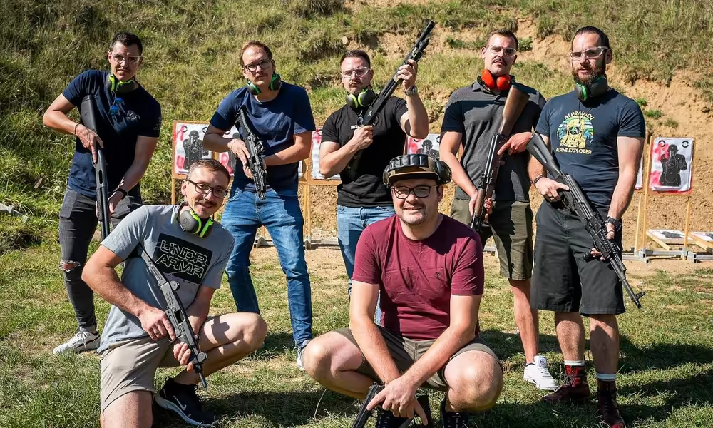 Tourists posing with rifles at the outdoor shooting range near Prague