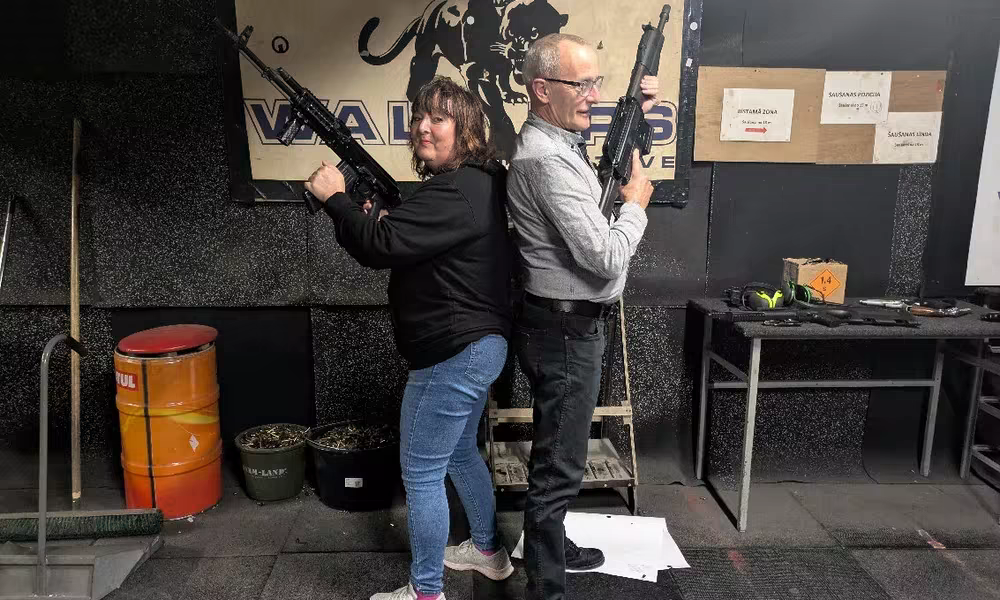 Couple posing with Kalashnikov rifles after the Riga movie shooting experience