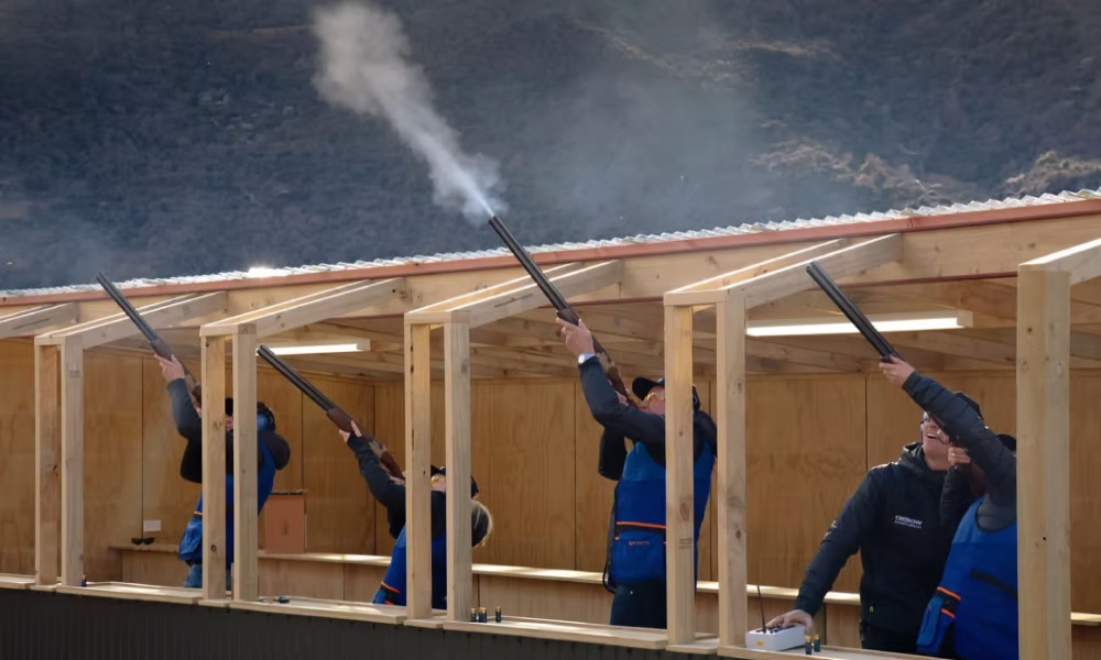 Four tourists clay target shooting at Oxbow Gun Club in the Gibbston Valley near Queenstown, New Zealand