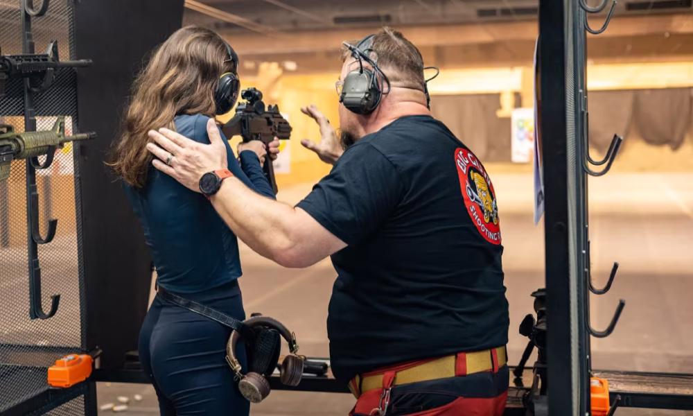 Instructor guiding a tourist at an indoor shooting range in Kraków, Poland