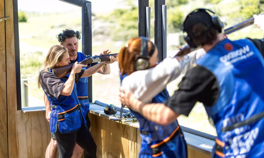 Instructor helping a visitor aim a shotgun during a clay target shooting session at Oxbow Gun Club Queenstown