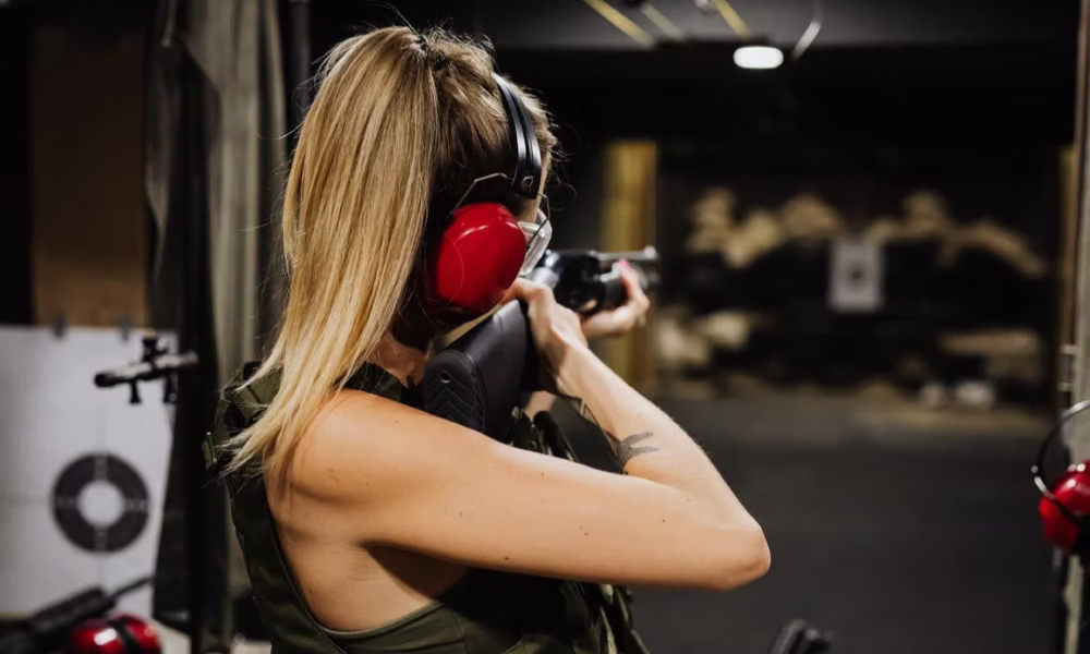 Woman aiming a rifle with ear protection at a combat shooting range near Krakow